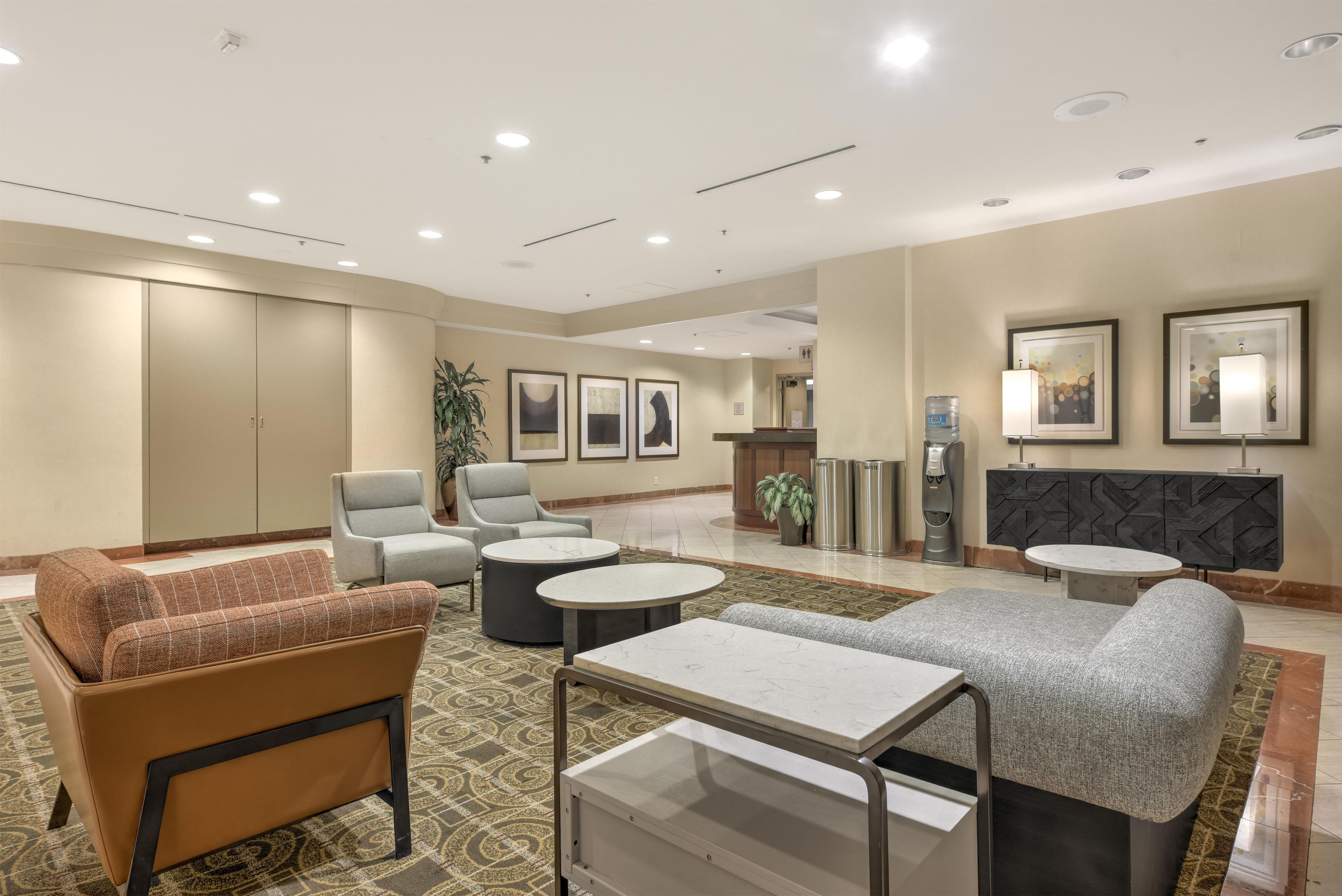 A hotel lobby with seating areas, a reception desk, and framed artwork on the walls.
