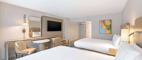 A hotel room with two beds, a desk, a chair, a TV, and a painting on the wall.