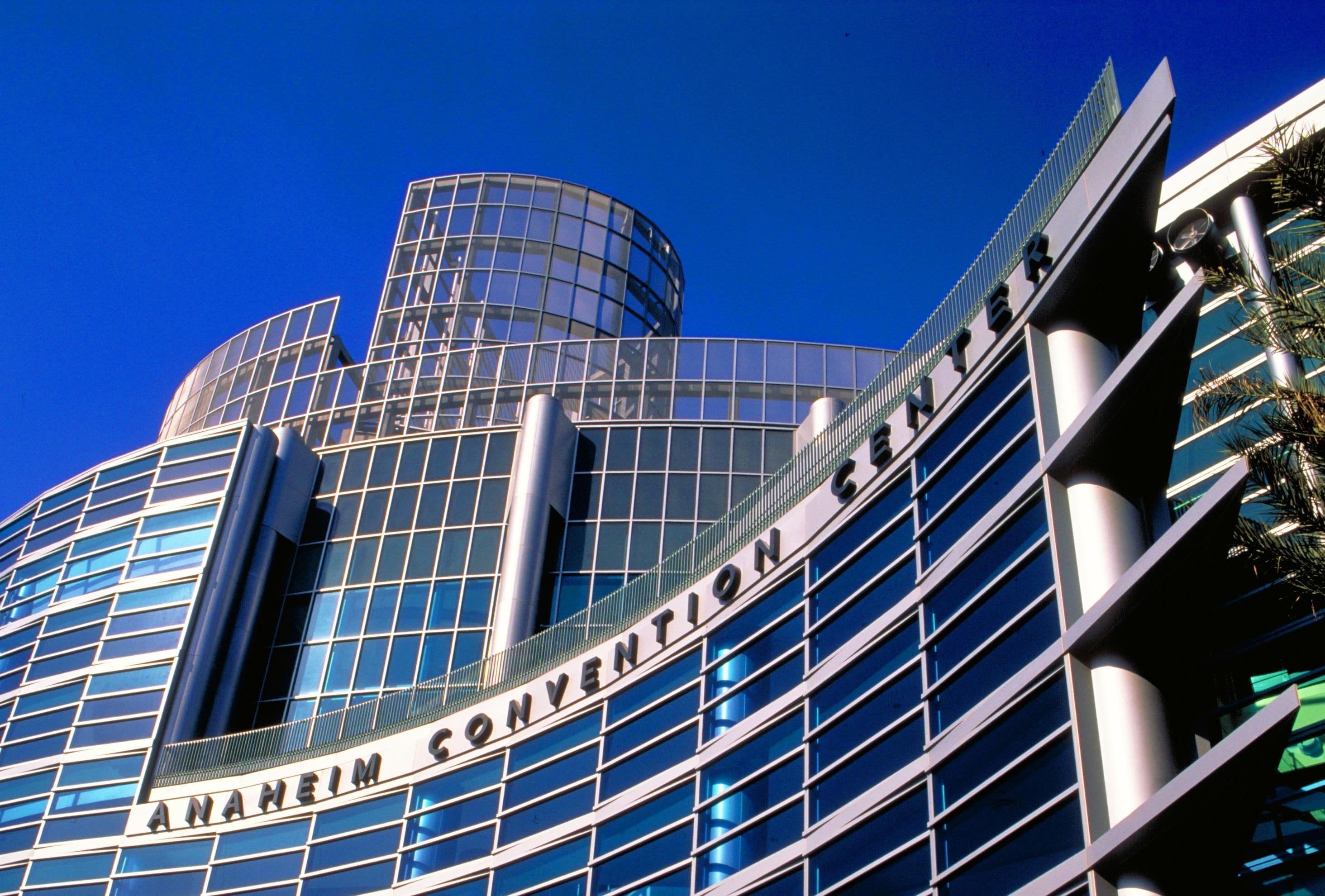 Un edificio moderno con fachada de vidrio y el texto 'ANAHEIM CONVENTION CENTER' en el costado.