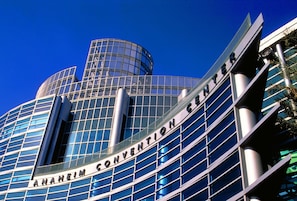 Un edificio moderno con fachada de vidrio y el texto 'ANAHEIM CONVENTION CENTER' en el costado.