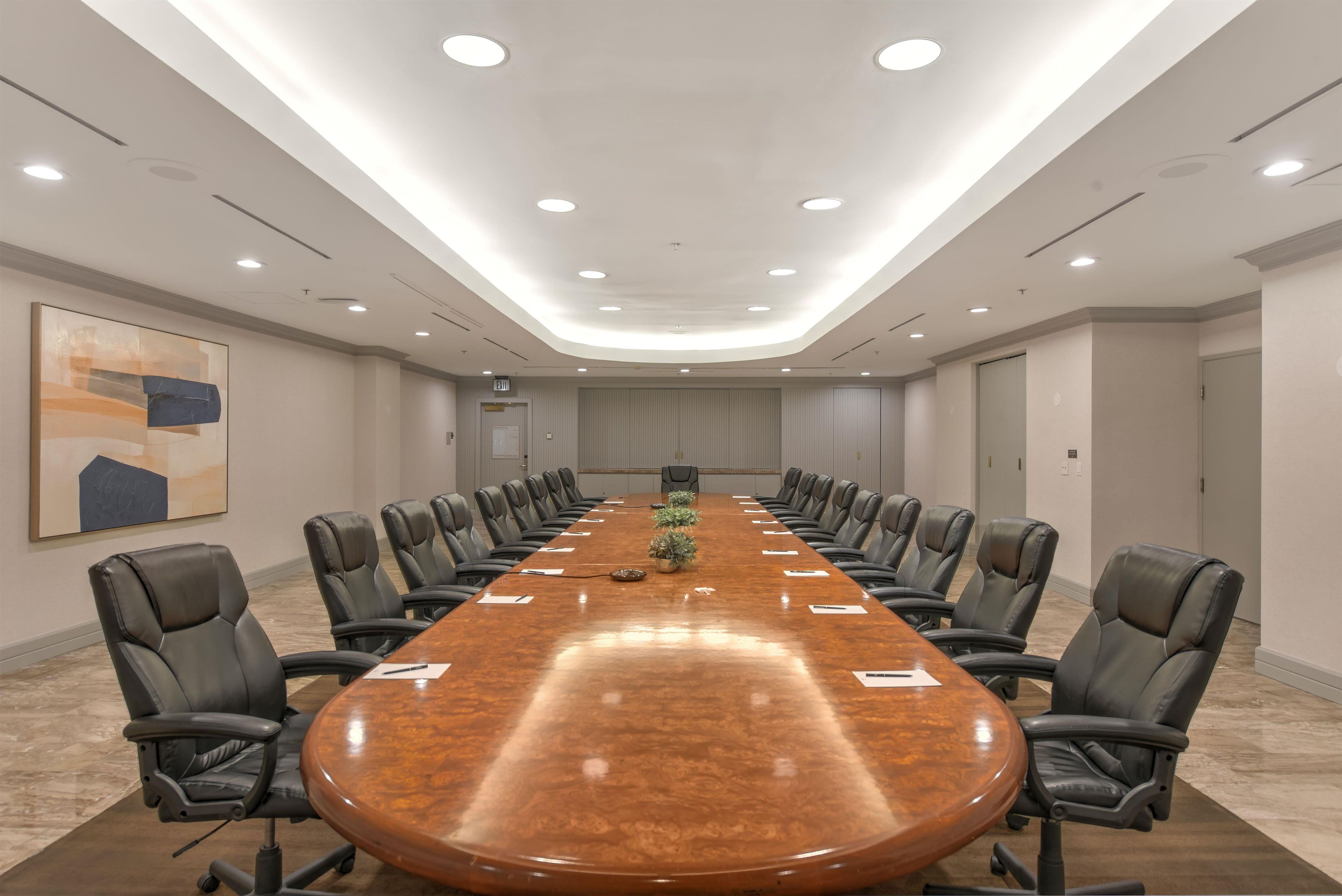A conference room with a long table, black chairs, and recessed ceiling lighting.