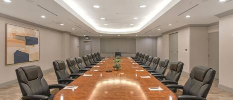 A conference room with a long table, black chairs, and recessed ceiling lighting.