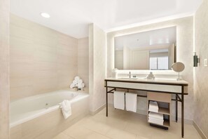 A modern bathroom with a bathtub, a vanity with a mirror, and towels.