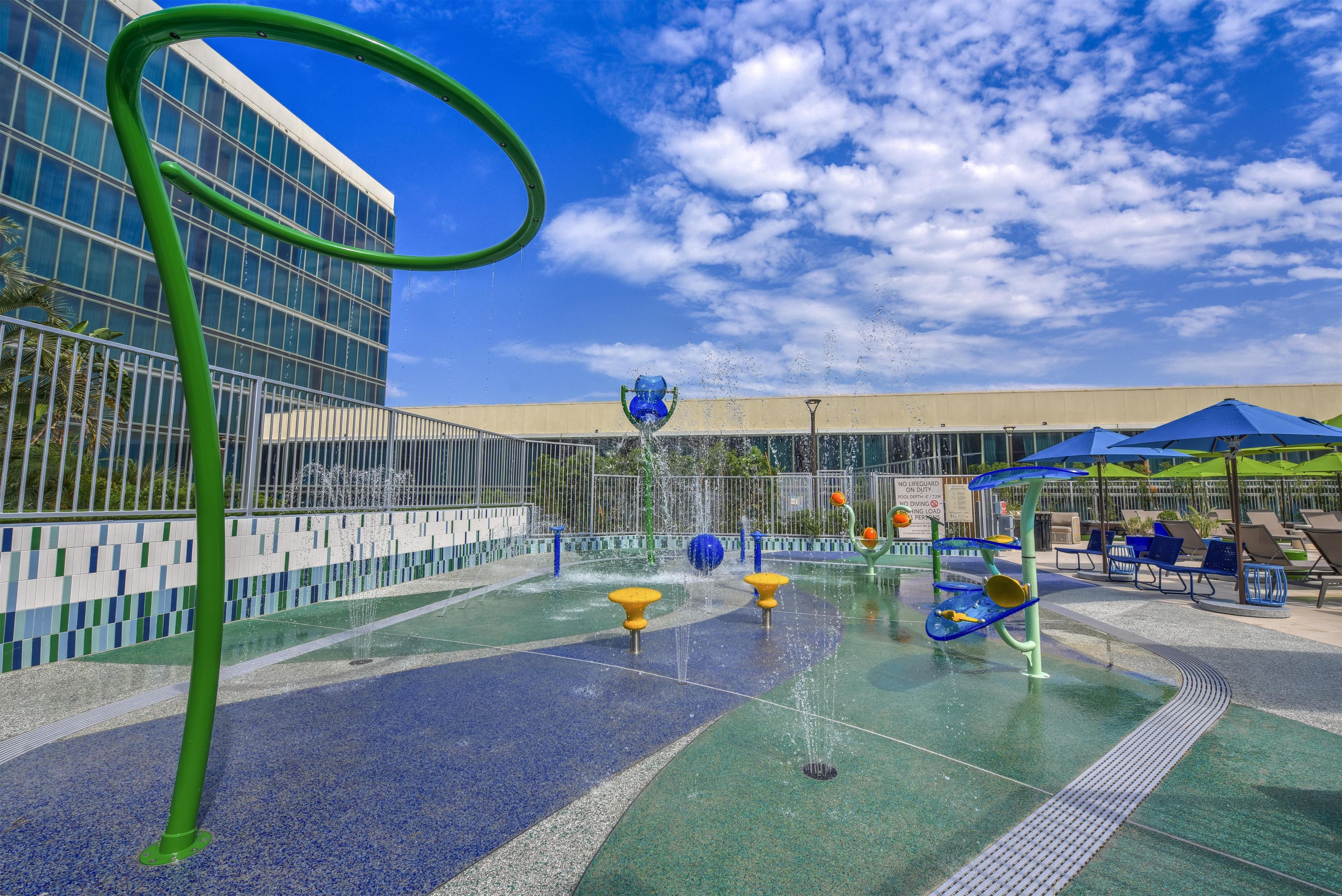 A water play area with multiple fountains and a green structure.