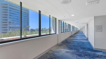 A corridor with large windows, a blue carpet, and a sign indicating the location.