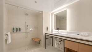 A modern bathroom with a walk-in shower, a large mirror, and a vanity with a sink and towel rack.