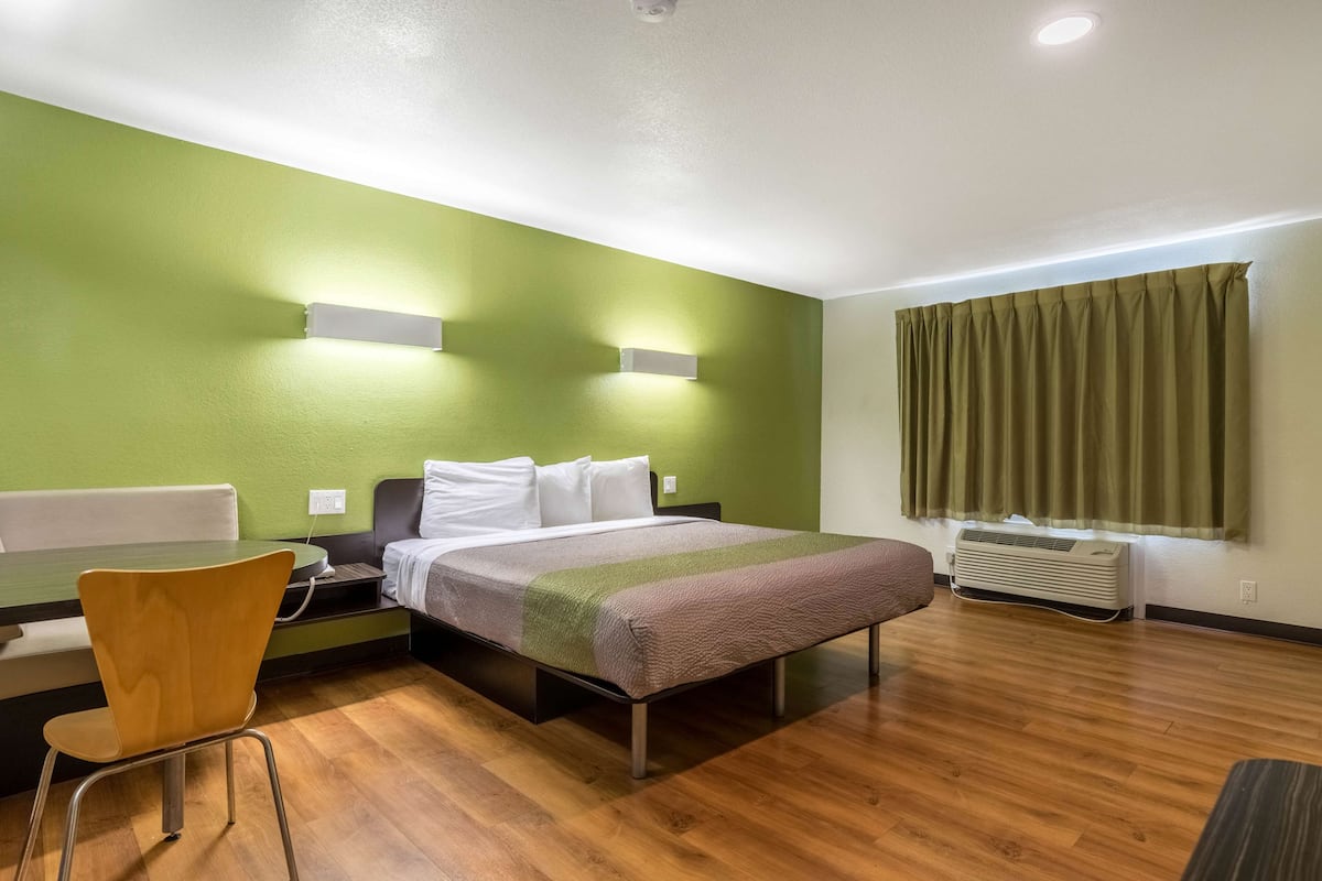 A hotel room with a bed, a desk, a chair, and a window with curtains.