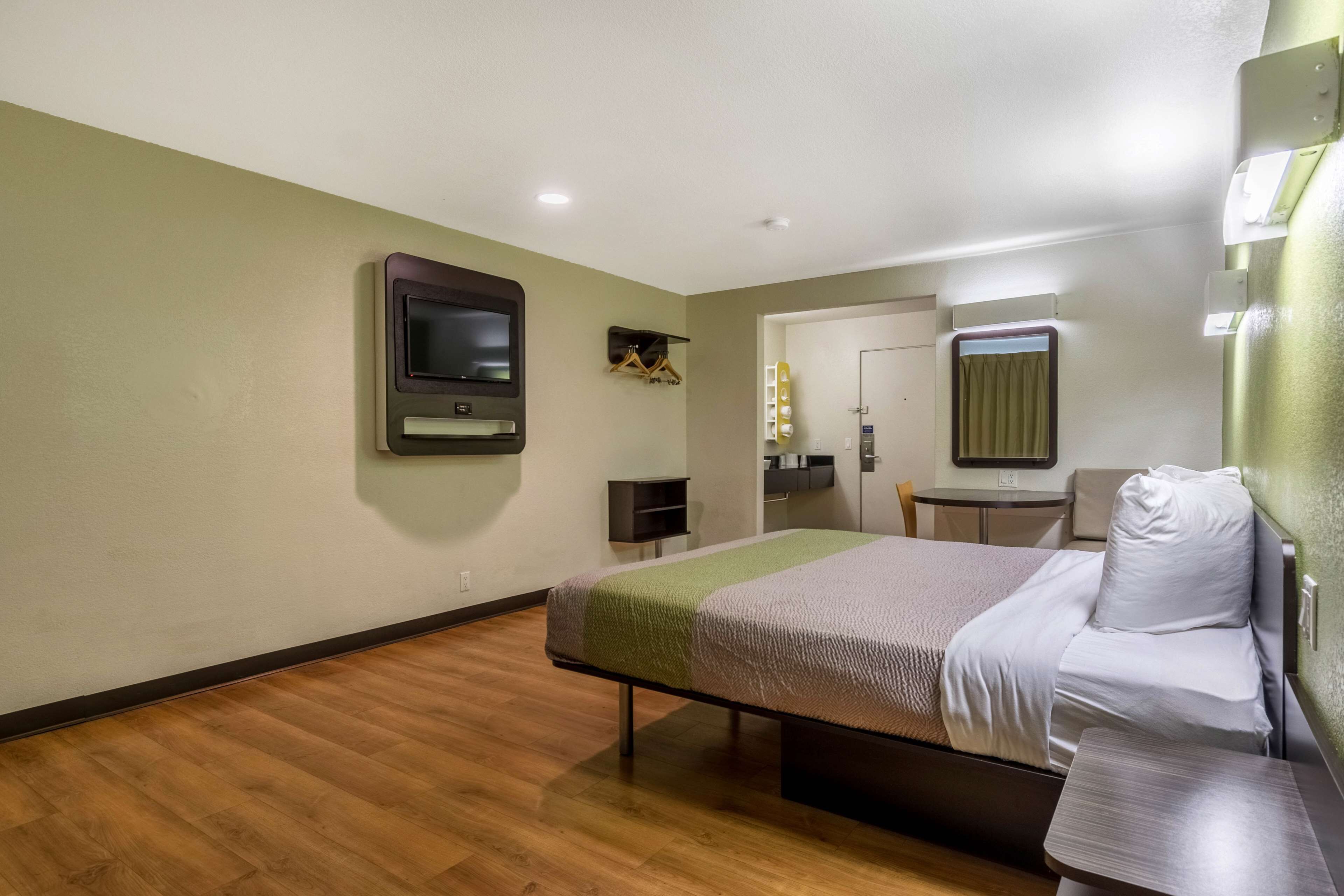 A hotel room with a bed, a television, a small table, and a chair.