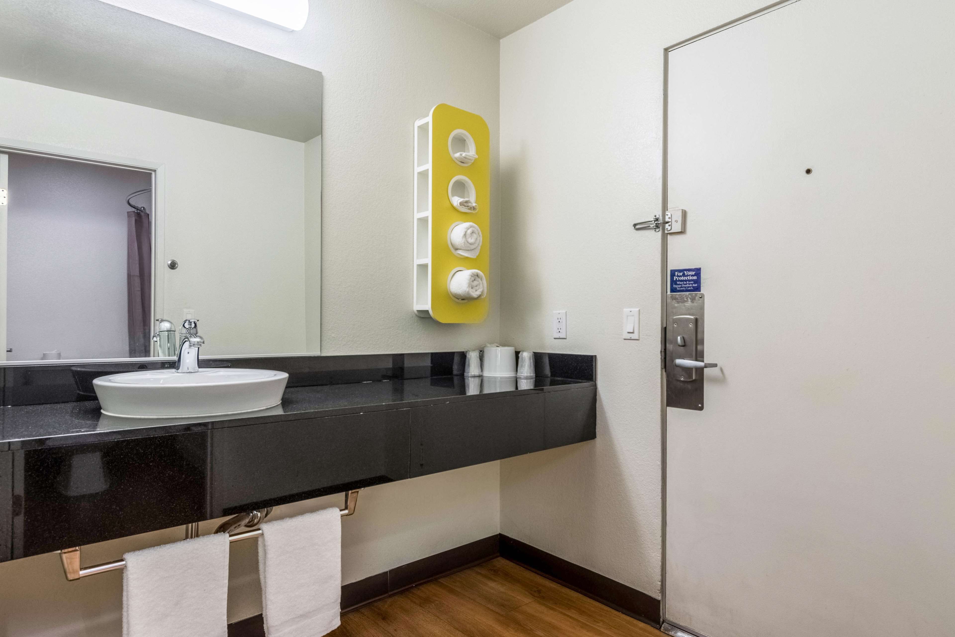 A bathroom with a white sink, black countertop, and a yellow towel warmer.