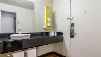 A bathroom with a white sink, black countertop, and a yellow towel warmer.