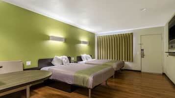 Habitación de hotel con dos camas, suelo de madera, paredes verdes y una puerta con cortina.