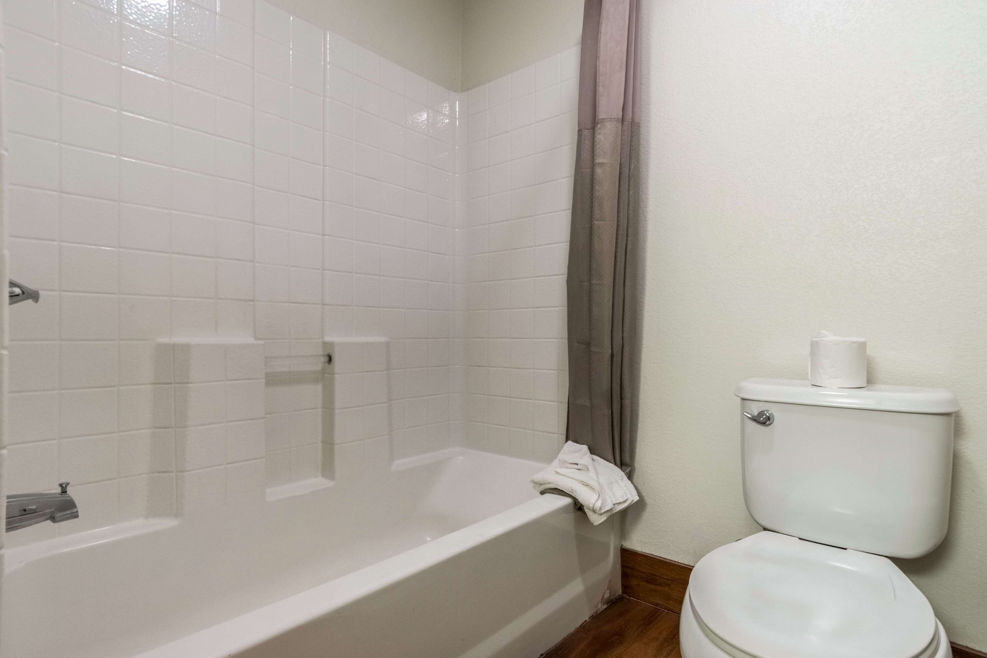 Une salle de bain avec une baignoire blanche, des toilettes et un rideau de douche.
