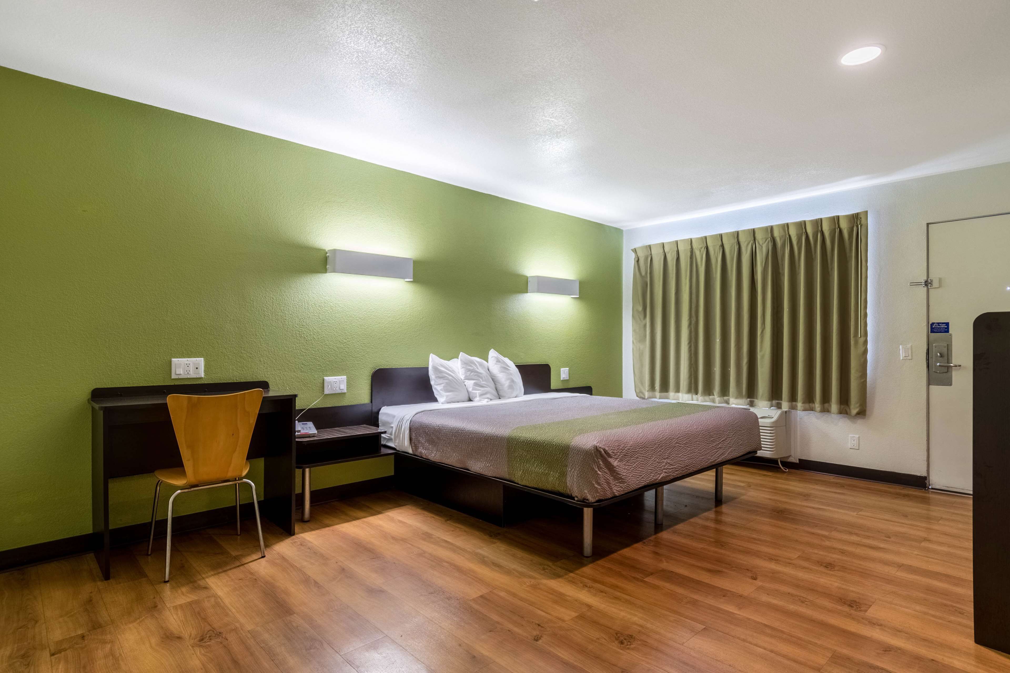 Una habitación de hotel con cama, escritorio, silla y armario.