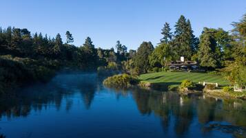 A serene lakeside view with a house and a well-maintained lawn.