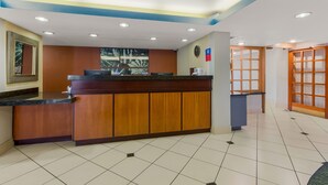 A reception area with a wooden counter, a clock, and a wall-mounted sign. - Revival Scottsdale Studios (Scottsdale)