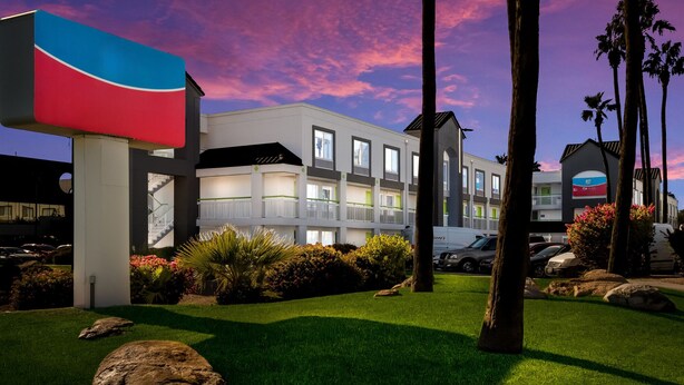 A modern hotel with a landscaped garden, large rocks, and palm trees. - Revival Scottsdale Studios (Scottsdale)