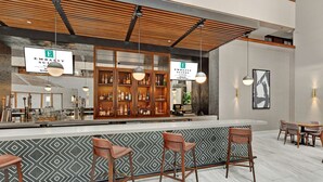Zona de bar moderna con techo de madera, minibar y taburetes.