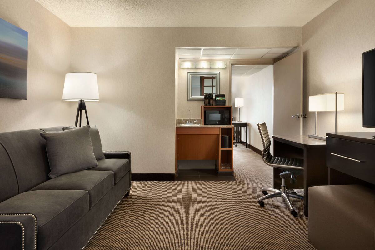 Ein Hotelzimmer mit Sofa, Schreibtisch, Stuhl und Fernseher.