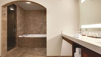 Un baño moderno con una bañera independiente, un espejo grande y un mueble de tocador con toallas.