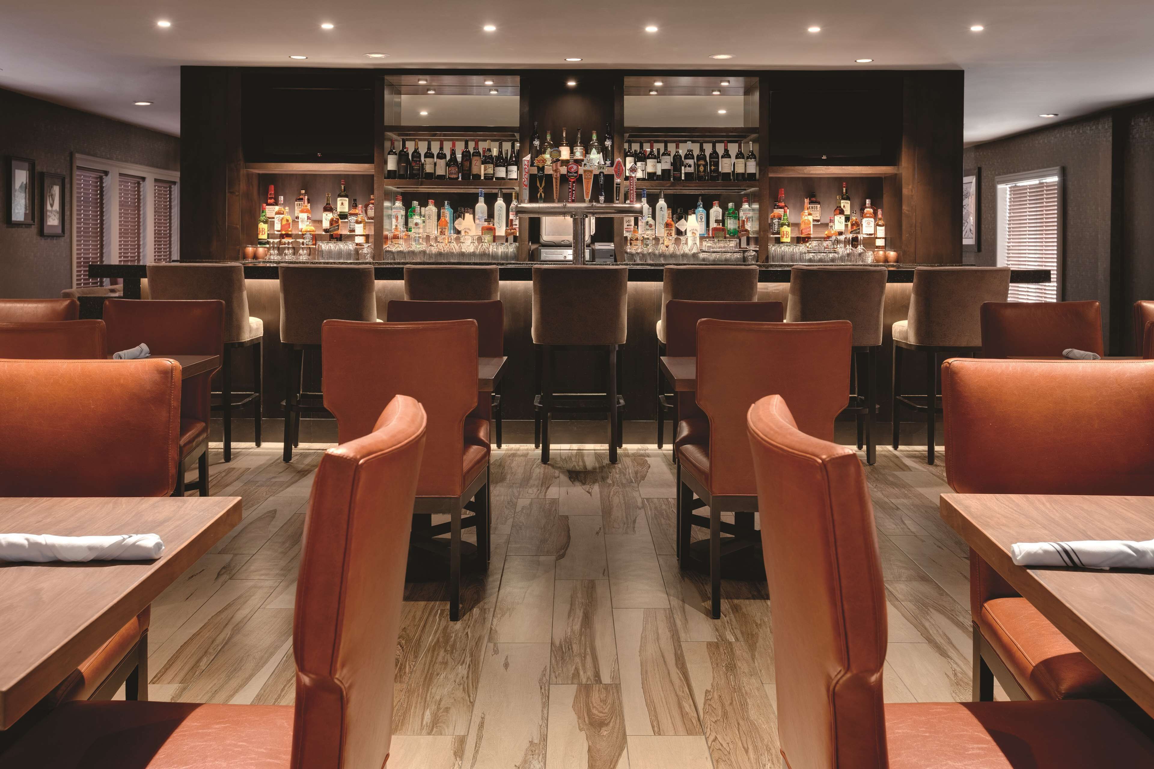 Un área de bar con diversas opciones de asientos, una barra bien surtida y una decoración de diseño moderno.