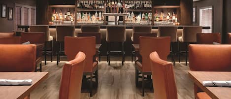 Un área de bar con diversas opciones de asientos, una barra bien surtida y una decoración de diseño moderno.