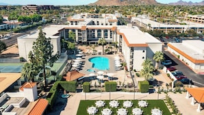 A hotel with a swimming pool, outdoor seating, and a mountain view. - Embassy Suites by Hilton Scottsdale Resort (Scottsdale)