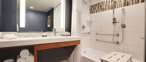 A modern bathroom with a large mirror, white sink, and a shower area with a glass door.