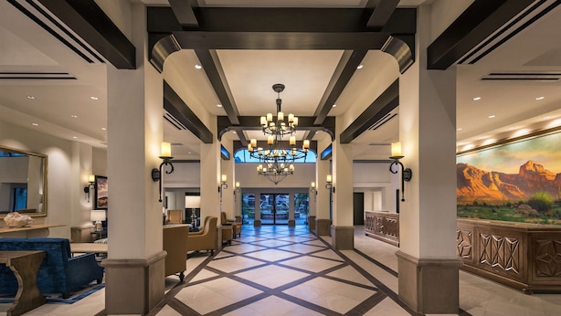A hotel lobby with a geometric floor pattern, a chandelier, and a mountain view mural. - Embassy Suites by Hilton Scottsdale Resort (Scottsdale)