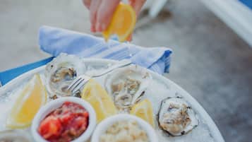 Een bord oesters met partjes citroen en een klein schaaltje saus.
