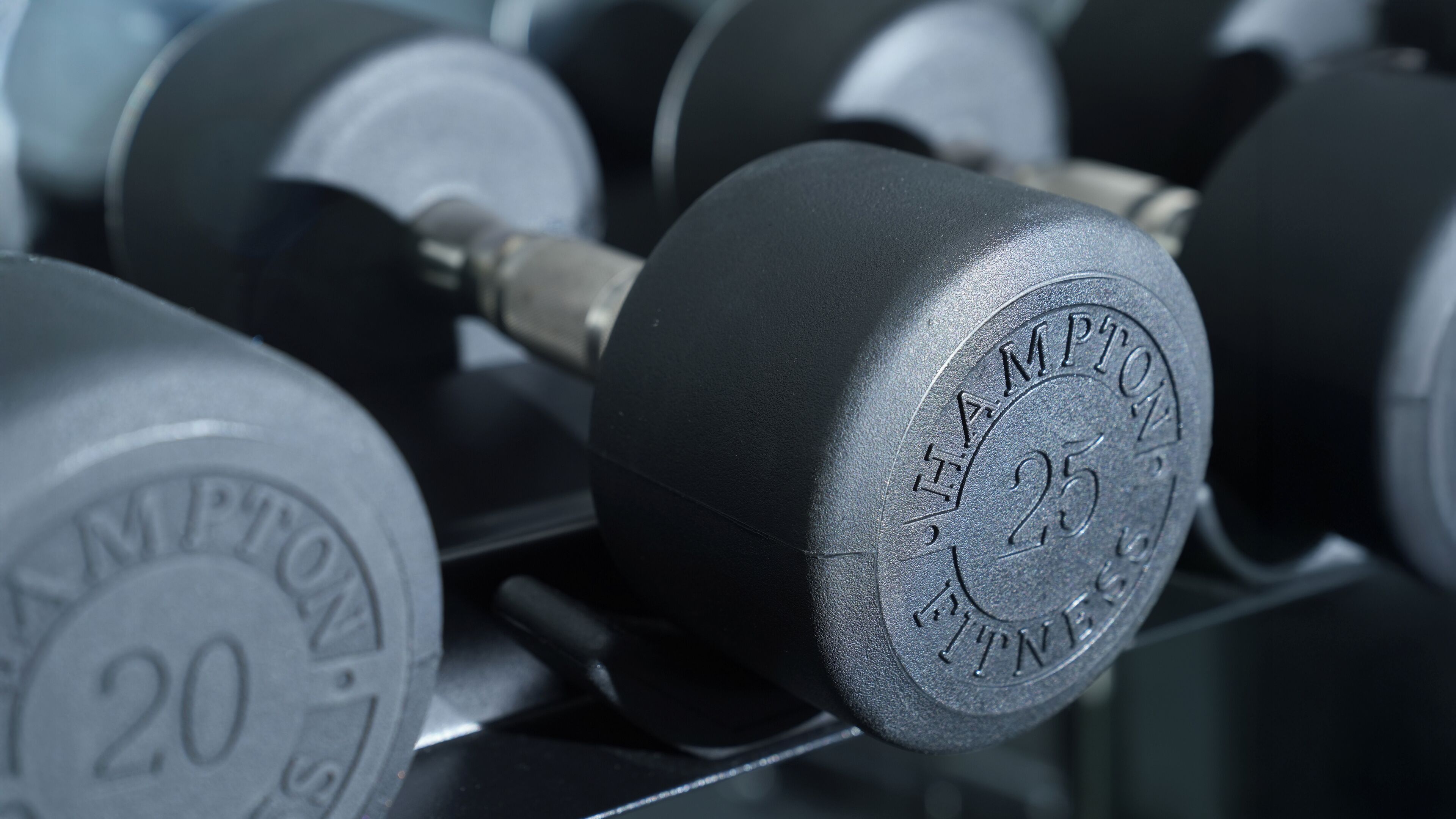 A close-up of a weightlifting dumbbell with the inscription "HAMPTON FITNESS" and the number "25".