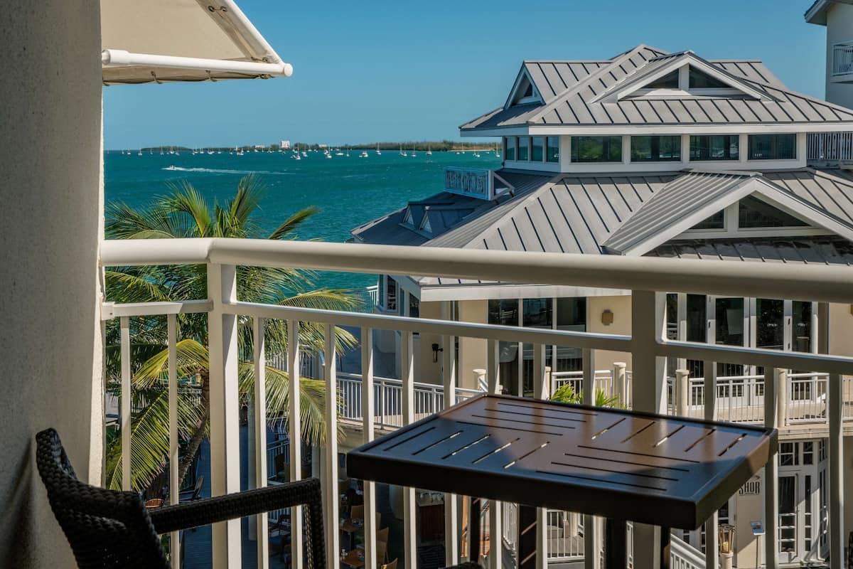A balcony with a view of the ocean and a distant pier.