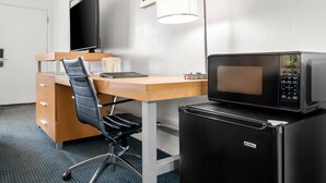 A hotel room with a desk, chair, television, microwave, and refrigerator. - Quality Inn Rock Springs - Green River (Rock Springs)