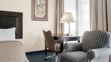 Une chambre d’hôtel avec un lit, un bureau, une chaise, une lampe et un tableau au mur.
