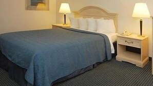 A hotel room with a bed, two bedside tables with lamps, a nightstand, and a framed picture on the wall.