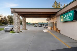 A Quality Inn by Choice Hotels with a stone pillar entrance, a covered parking area, and a clear sky. - Quality Inn Rock Springs - Green River (Rock Springs)
