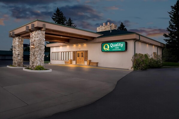 Entrada de un hotel con un pilar de piedra, una puerta de madera y un letrero que indica que es un Quality Inn de Choice Hotels.