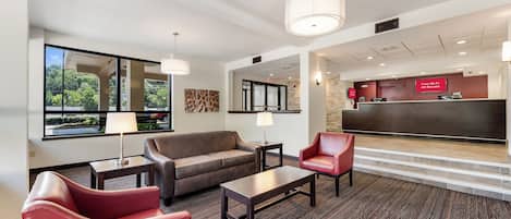 A hotel lobby with a reception desk, a sofa, two armchairs, and a coffee table.