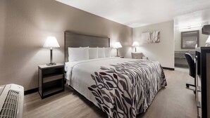 A hotel room with a large bed, two bedside tables with lamps, a desk with a chair, and a wall-mounted TV. - Red Roof Inn Birmingham South (Birmingham)