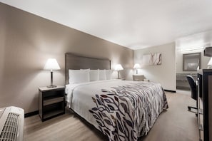 A hotel room with a large bed, two bedside tables with lamps, a desk with a chair, and a wall-mounted TV. - Red Roof Inn Birmingham South (Birmingham)
