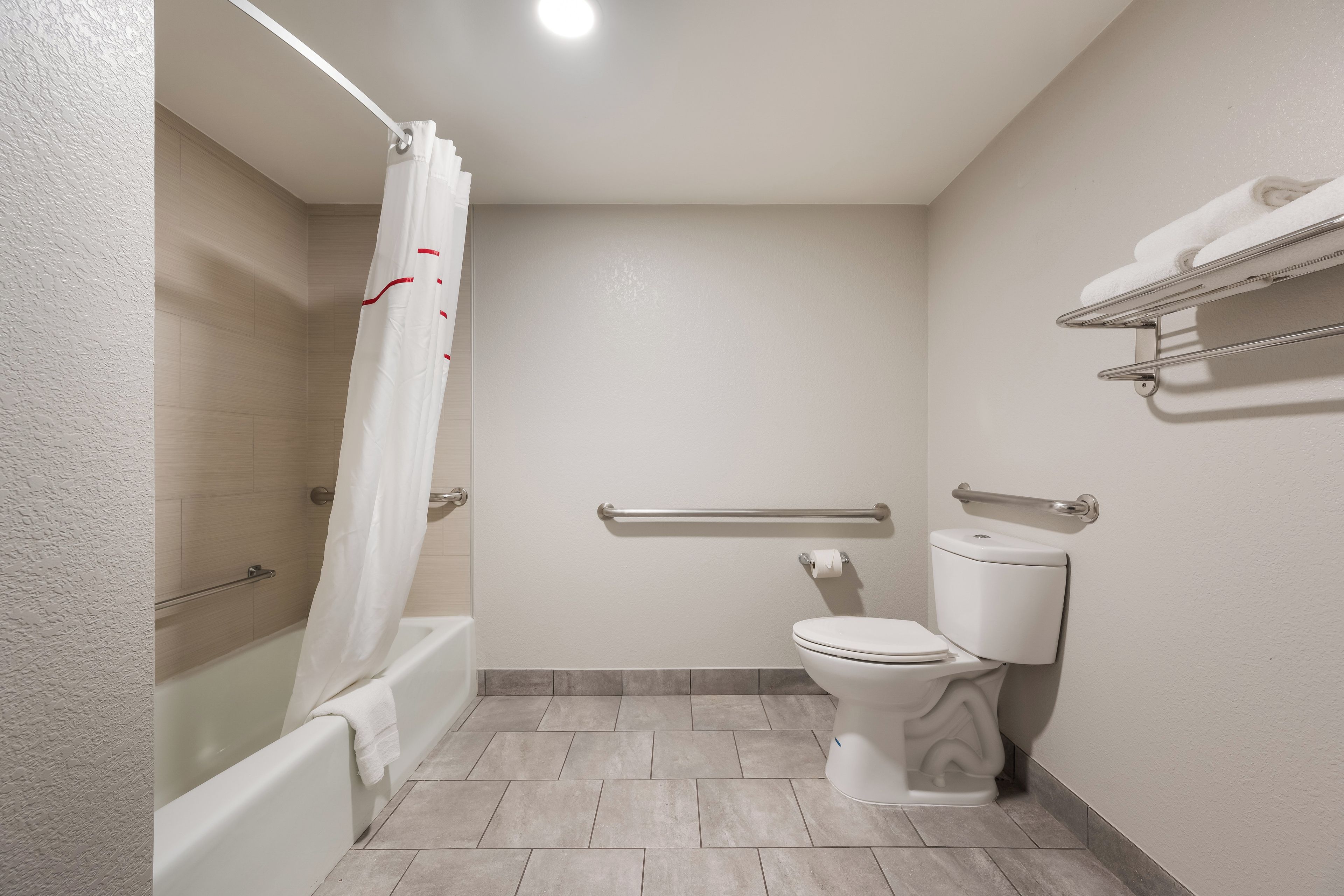 A bathroom with a bathtub, toilet, and shower curtain.