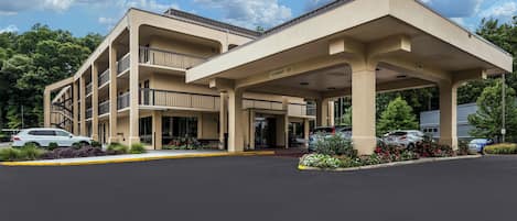 Ein mehrstöckiges Hotel mit überdachter Eingangshalle und Parkplatz.