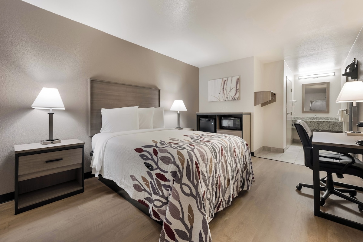 A hotel room with a bed, bedside tables, a desk, and a chair.