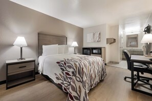 Una habitación de hotel con una cama, mesitas de noche, un escritorio y una silla.