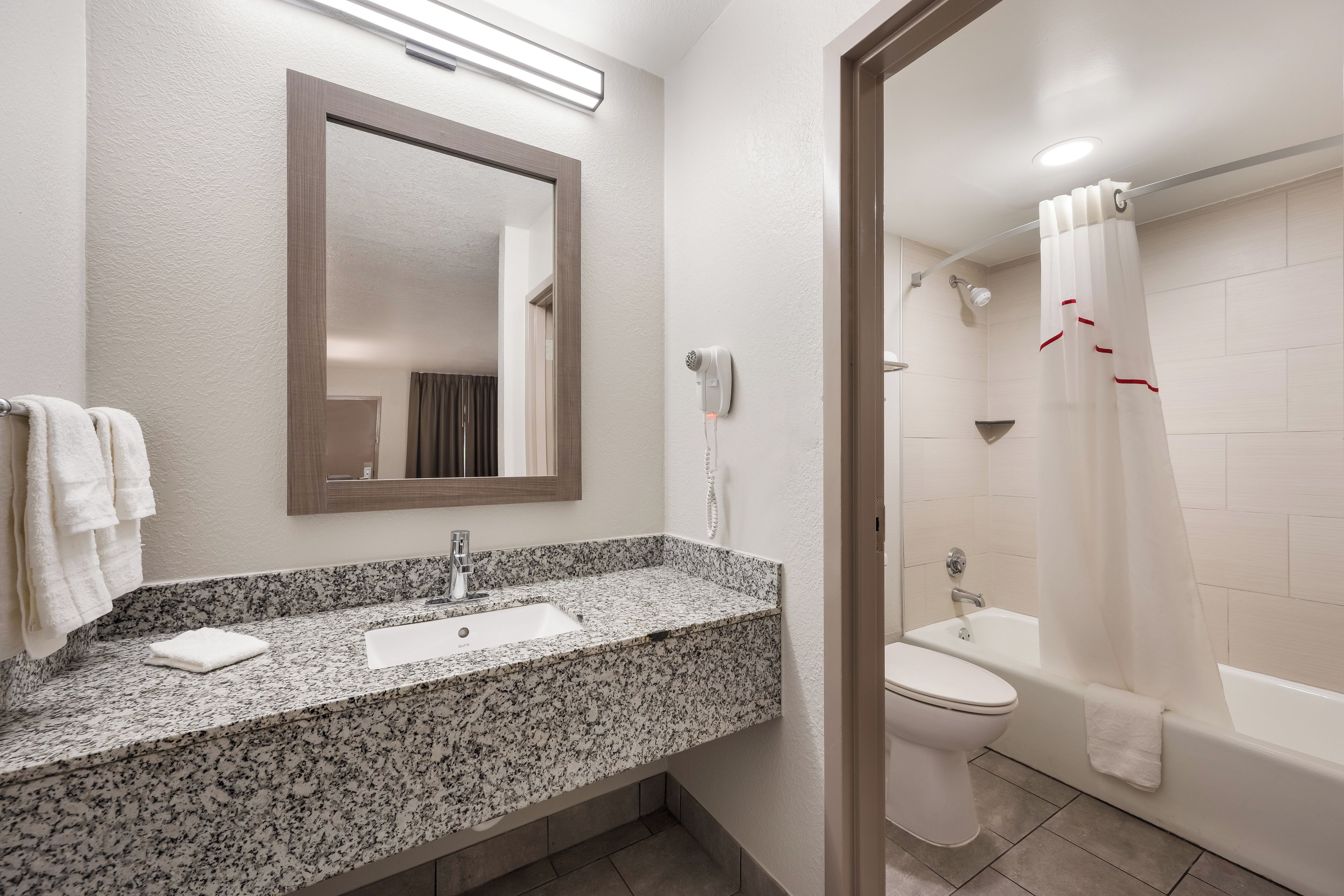 Ein Badezimmer mit Marmorwaschtisch, einem Spiegel, einem Fön, einer Toilette und einer Duschkabine.