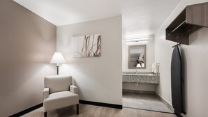 Un baño moderno con una silla, un perchero de pared, un dispensador de toallas y un espejo.