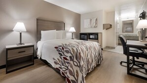 Una habitación de hotel con una cama, mesitas de noche, un escritorio y una silla.