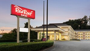 Un Red Roof Inn con un letrero grande, un acceso cubierto y un estacionamiento.