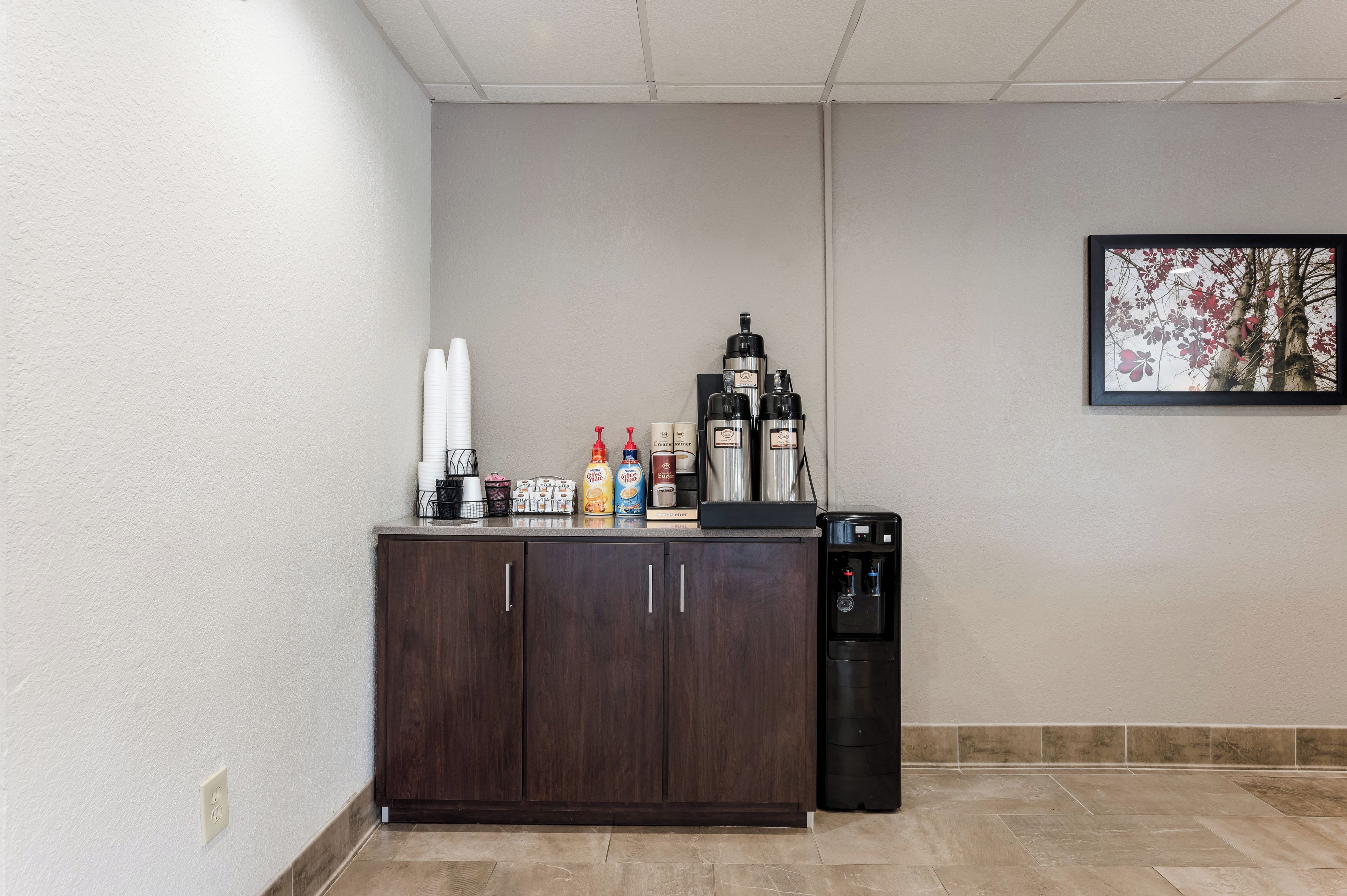A kitchenette with a coffee maker, sugar dispenser, and coffee creamer on the counter.