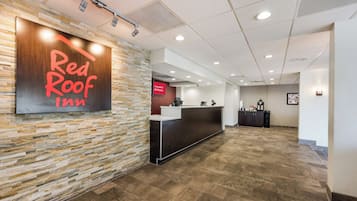 A reception area with a stone wall, a Red Roof Inn sign, a reception desk, and a 'Free Wi-Fi All Rooms' sign.