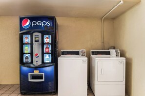 A vending machine with a Pepsi logo and various drink options, next to two white commercial washers. - Red Roof Inn Birmingham South (Birmingham)